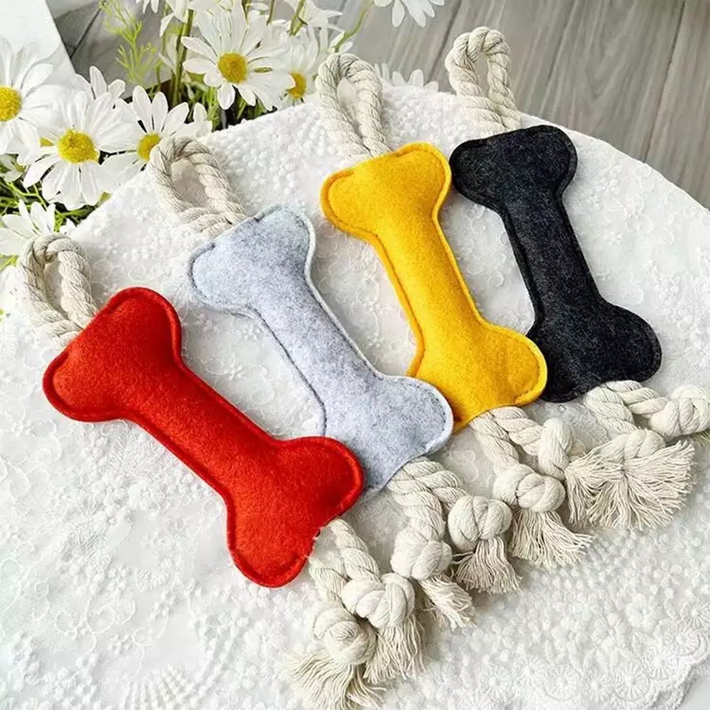 felt bone shape dog chew toy with rope on table